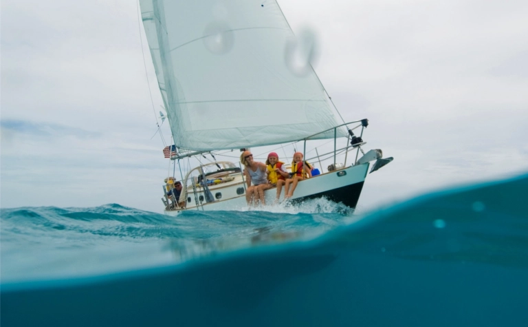 Ein Paar mit 2 Kidner auf einem Segelboot, alle tragen eine Schwimmweste